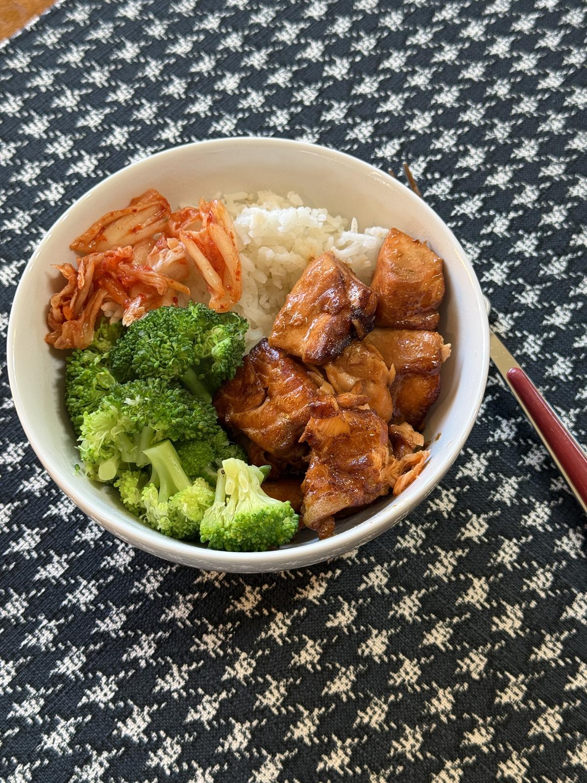 Teriyaki Salmon, rice, broccoli and kimchi in a white bowl