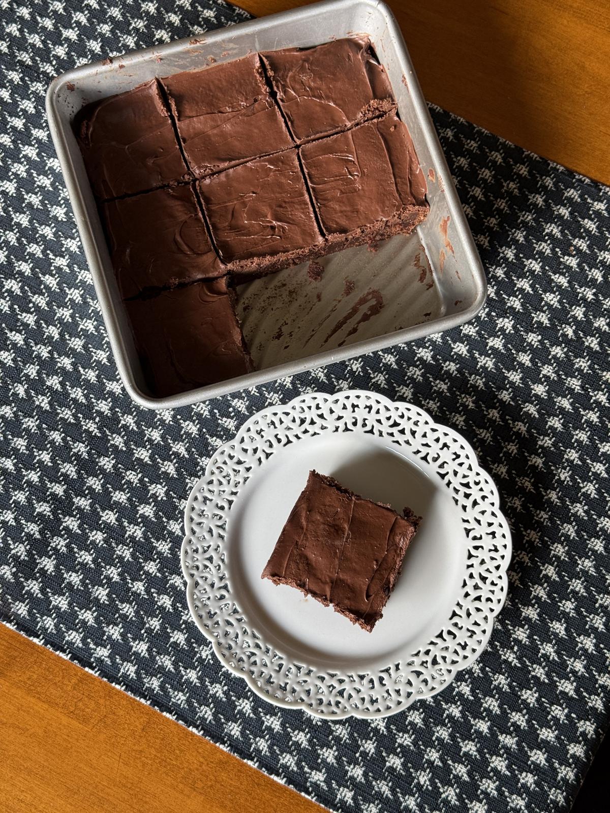 cake brownie in metal pan with one brownie on white plate on table