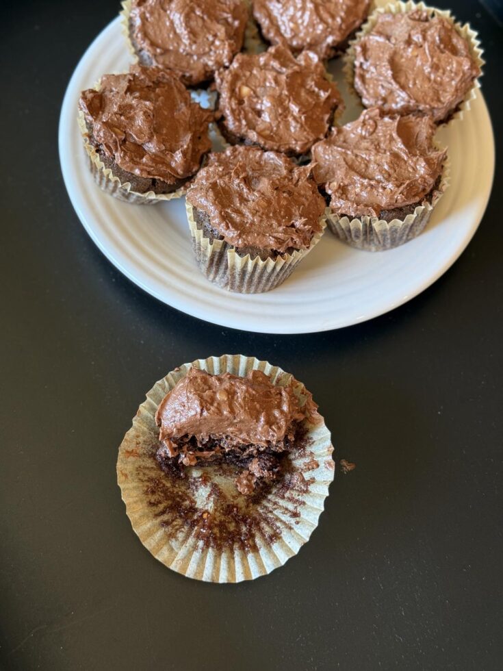 Chocolate Toffee Cupcakes on white plate with partially eaten cupcake on black background