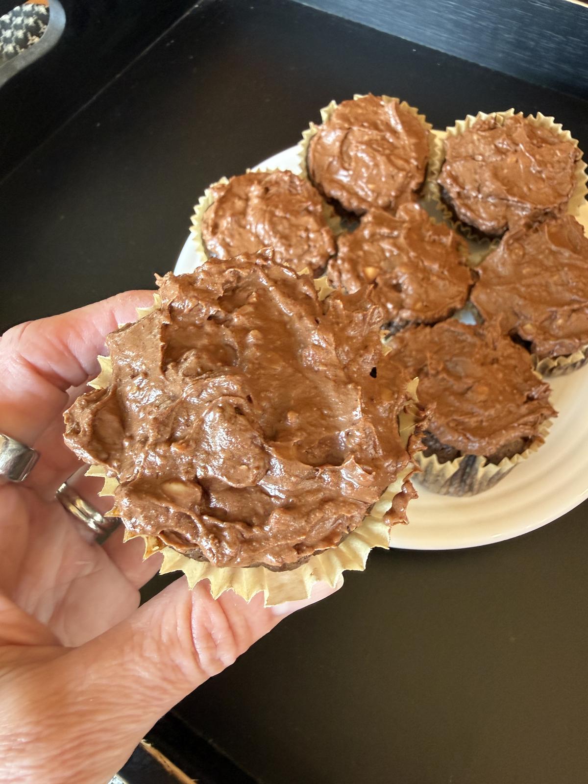 Chocolate Toffee Cupcakes on white plate with hand holding cupcake on black background