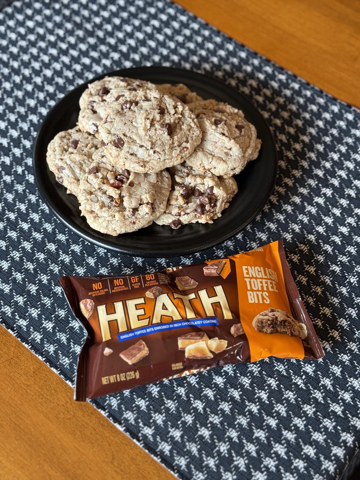 bag of heath toffee bits with cookies on black plate