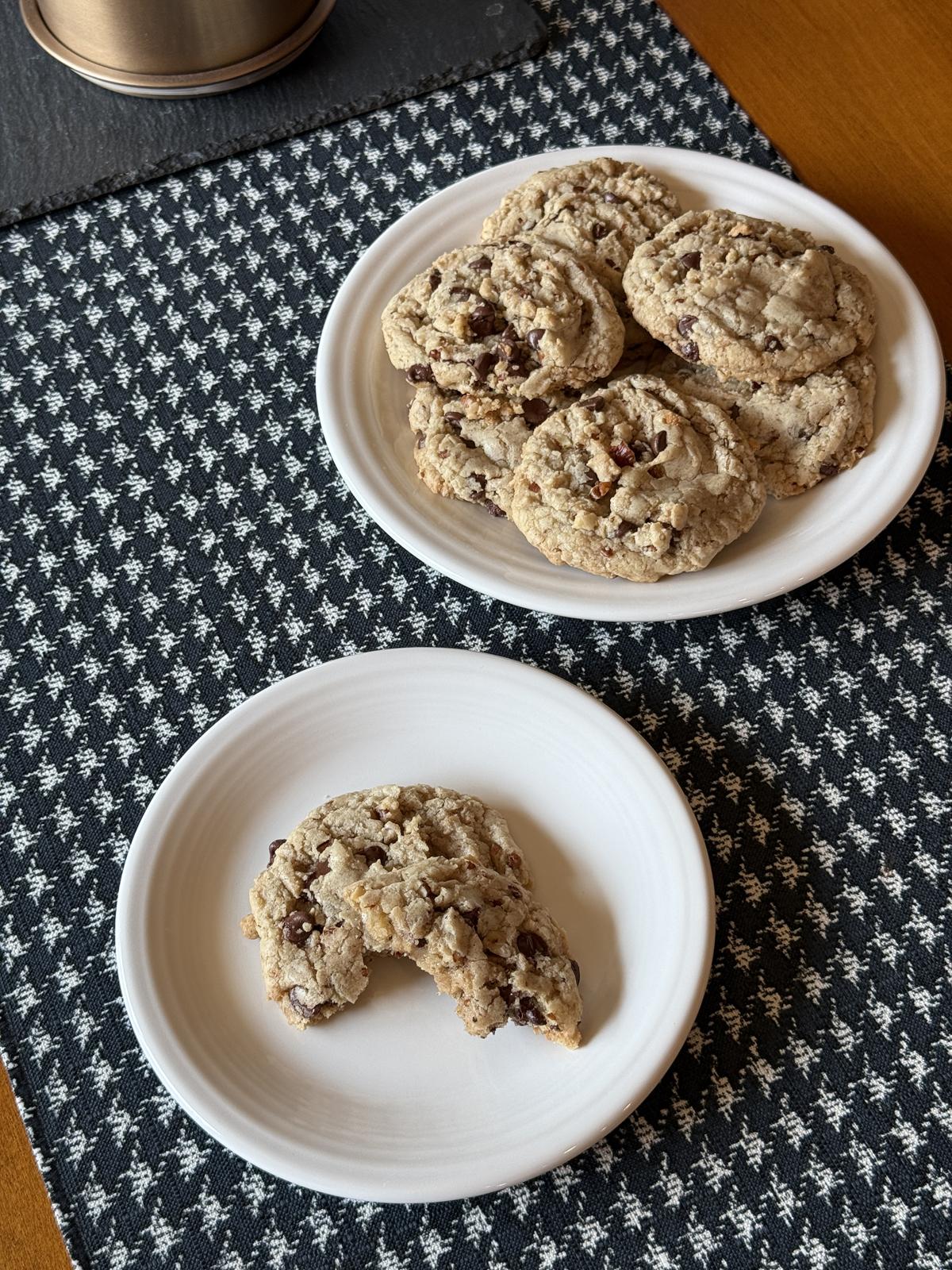white plate of gluten free chocolate toffee pecan cookies on black and white table runner