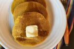 gluten free pumpkin pancakes with butter on white plate and striped napkin