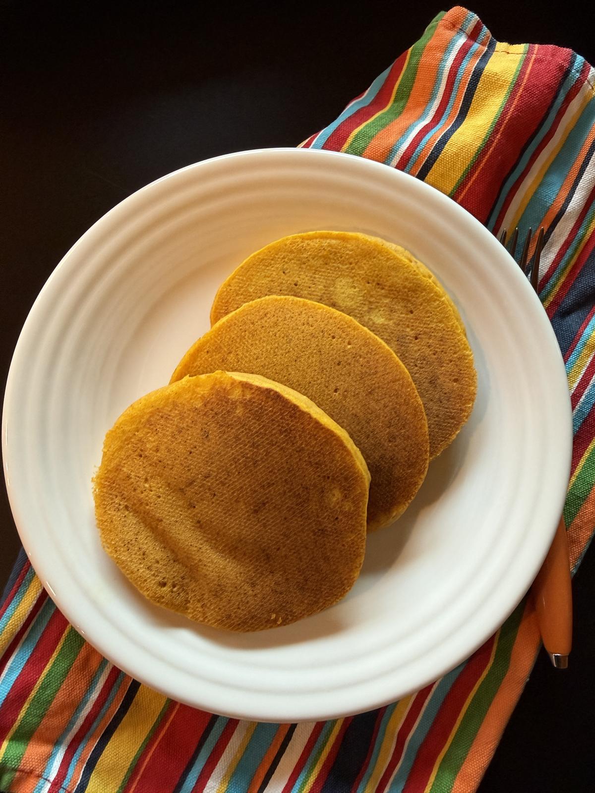 gluten free pumpkin pancakes on white plate and striped napkin