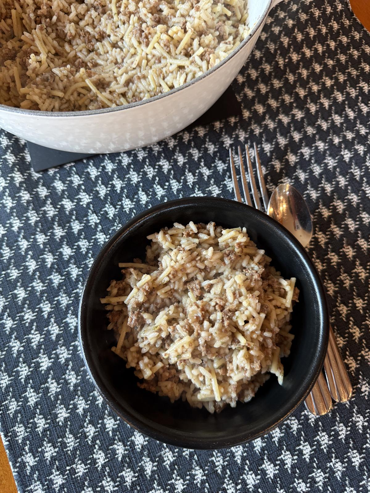Homemade Rice A Roni with Ground Beef in black bowl with pan in background